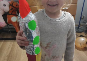Uśmiechnięta dziewczynka trzyma kolorową rakietę